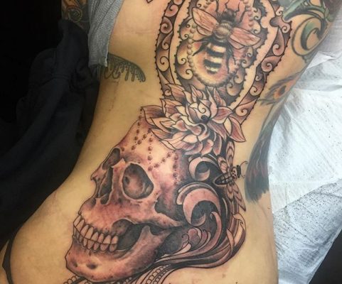skull and bee rib tattoo